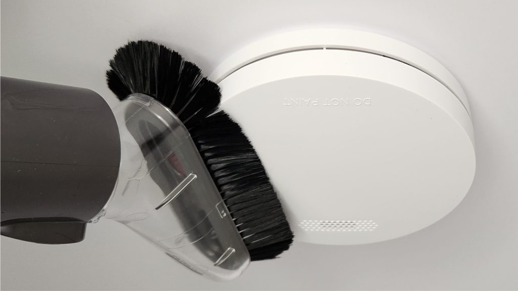 Interconnected smoke alarms cleaning with soft brush attachment from vacuum
